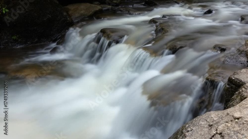 Cascading Waters - A Serene River Flowing Over Rocks.
