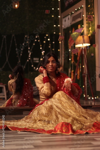 Portrait of an Indian Nepali woman wearing traditional red and golden lehenga sitting gracefully indoors with festive lights in background