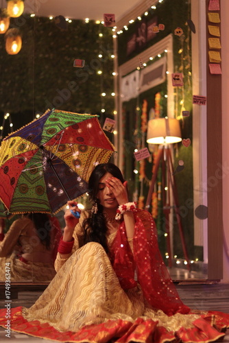 Nepali Indian girl in red and yellow traditional dress holding colorful umbrella during festive celebration
