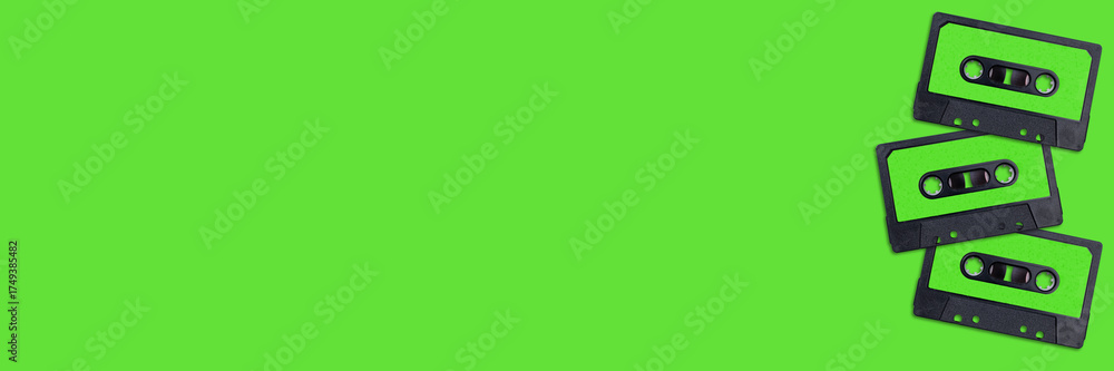 Fototapeta premium Top view of vintage audio cassette tapes flat lay on colorful green background. Creative 80s Banner. Retro minimal Pop Art design. music concept.