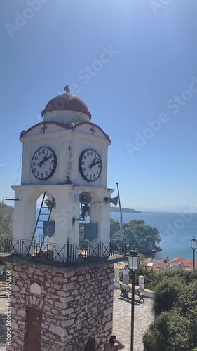 Historic clock tower overlooking the rooftops of Skiathos Town on the Greek island of Skiathos. This panoramic view captures whitewashed houses with terracotta roofs, the blue Aegean Sea