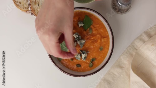 hands put blue cheese pumpkin cream soup overhead view