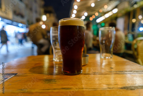 View of a pint of Guinness beer at a table outdoors at night in Paris France