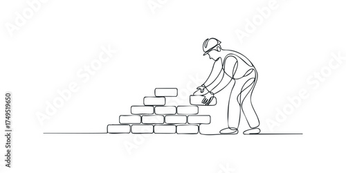 Worker places brick on construction site wall