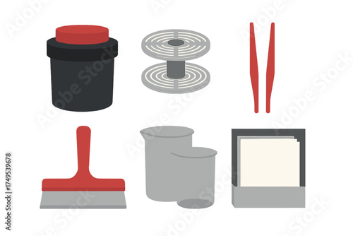 Essential darkroom tools collection for analog film photography processing: developing tank, reel, tongs, and beakers