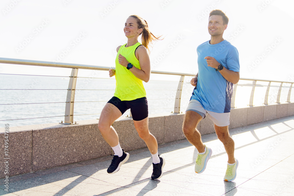 Fototapeta premium Couple jogging along a coastal pathway during early morning exercise