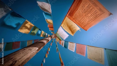 Colorful Tibetan prayer flags strung between tall wooden poles, fluttering in a clear blue sky.