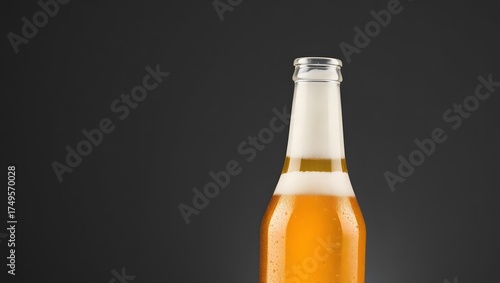 Cold glass bottle of brown lager beer on a black background with light and foam