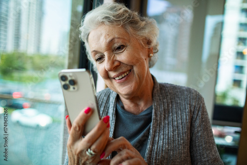 Happy senior woman using smartphone indoors
