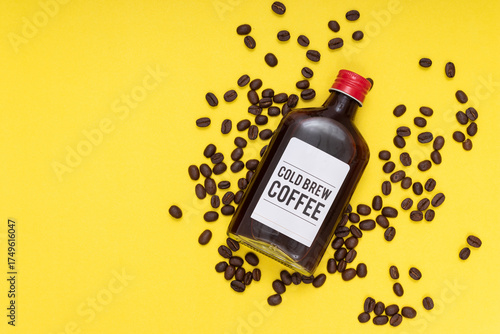 cold brew coffee bottle with coffee beans, yellow background, flat layout