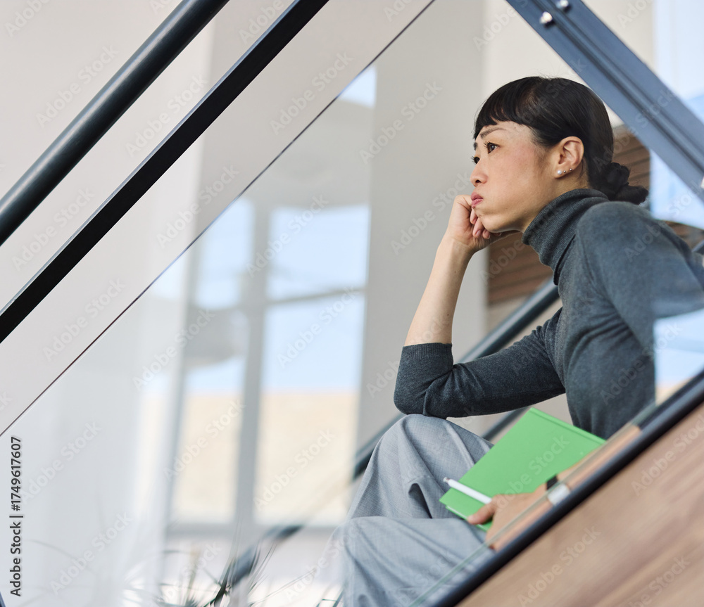 Fototapeta premium Portrait of a young businesswoman sitting on stairsin office, with headache, sick, tired or fatigue while working late . Burnout, stress and deadline concept