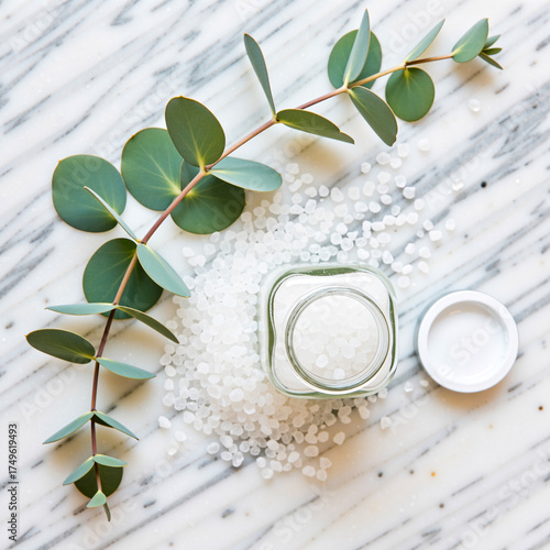 Eucalyptus leaves and glass jar with bath salts on marble surface  