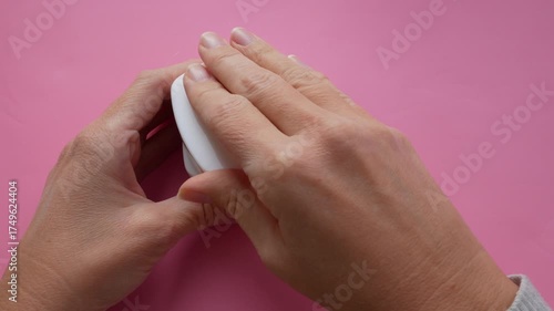 woman hands with cream cosmetic bottles on pink background, cold season hands skin protection. Top view