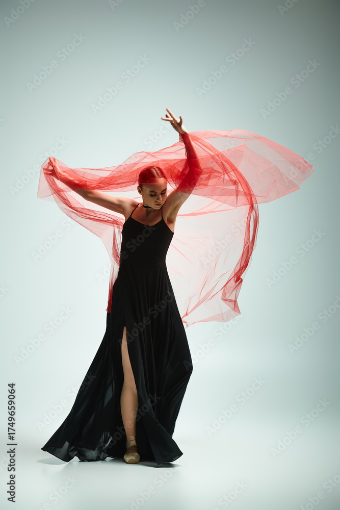 Naklejka premium Ballet dancer showcasing elegance with flowing red fabric in a minimalist studio setting