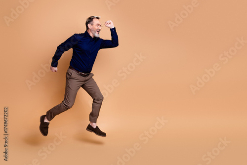 Photos Mature businessman wearing formal attire poses energetically against a beige bac