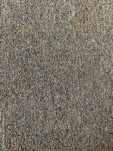 Detailed full-frame background of a dense woven loop pile carpet featuring a subtle pattern in mixed brown, gray, and muted green yarns. Interior Design concept