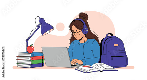 A young student wearing headphones studies diligently at a laptop with a backpack nearby.