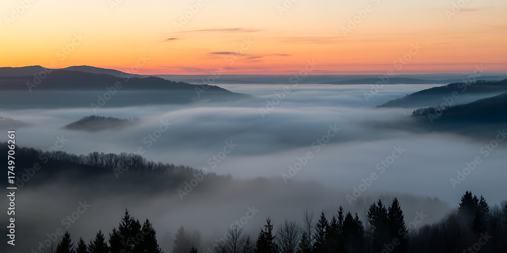 Fototapeta premium Mist-filled valley nestled among rolling hills under a vibrant, colorful sunrise sky.