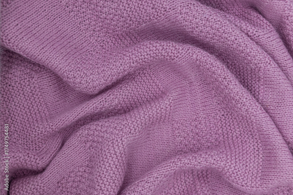 Fototapeta premium Purple knit fabric as a background. Wool knit texture. Purple knitted fabric surface with soft folds. Textile material for design. Purple knitted texture.
