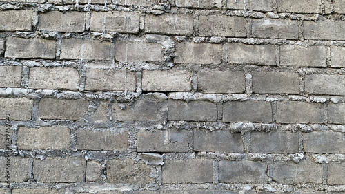 Detailed full-frame background of a rugged exterior wall constructed from rough gray concrete blocks joined by thick, overflowing white cement mortar. Construction concept