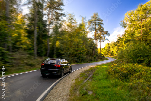 Ein fahrendes Auto auf einer sehr ländlichen Straße während die Sonne scheint im Herbst