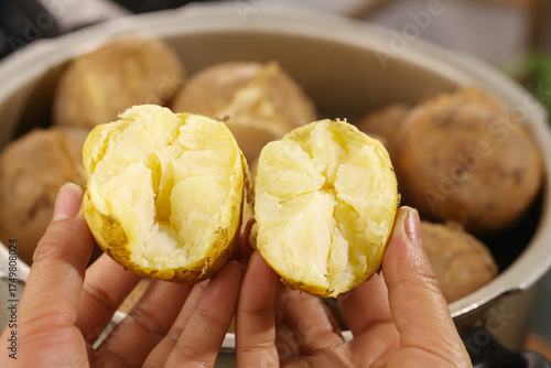 Tableau sur toile Heart-shaped steamed potatoes with white fluffy interior held in hands closeup
