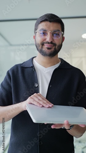 Professional man working on laptop in modern office with large windows and contemporary design during business hours