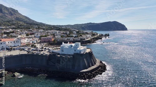 Beautiful white church Santa Maria del Soccorso
in Forio of Ischia island in Italy coastal drone shot with deep blue sea waves, cliffs and sunny weather. 