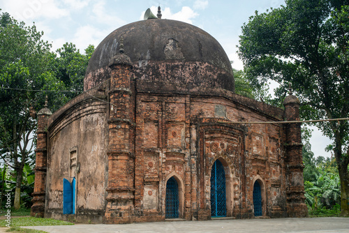 Old brick mosque with a large dome, surrounded by trees