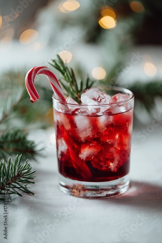 Festive Red Drink With Ice and a Candy Cane Surrounded by Greenery During the...
