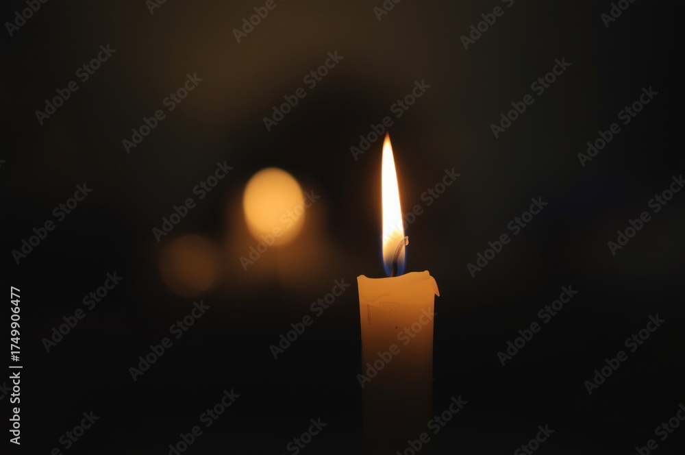 Fototapeta premium Close-Up of a Glowing Candle Flame Casting a Warm and Ethereal Light in the Darkness