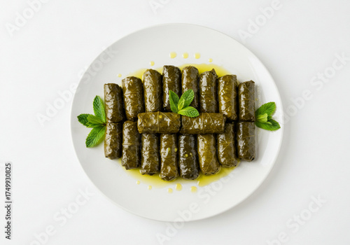 Stuffed grape leaves arranged on a plate with garnish of mint  
