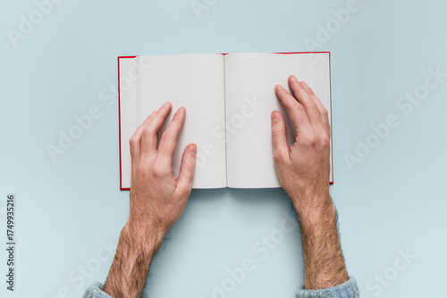 Tableau sur toile Male hands holding an open notebook with lined blank pages