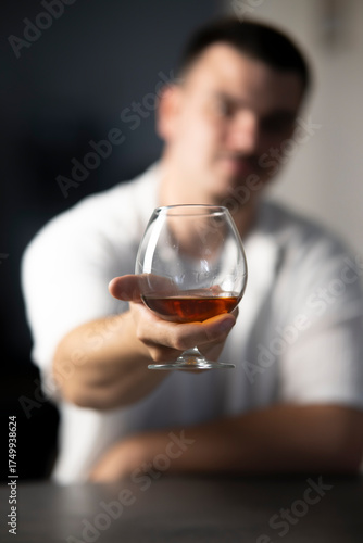 jeune homme flou tendant la main avec un verre de cognac pour fêter un évènement, 