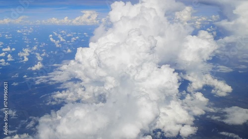 Through the airplane window, clouds roll by like soft mountains of white.