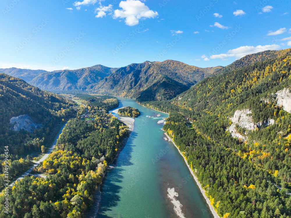 Fototapeta premium Expansive aerial panorama of the wide, turquoise Katun River flowing between two heavily forested mountain ranges in a sunny, clear day