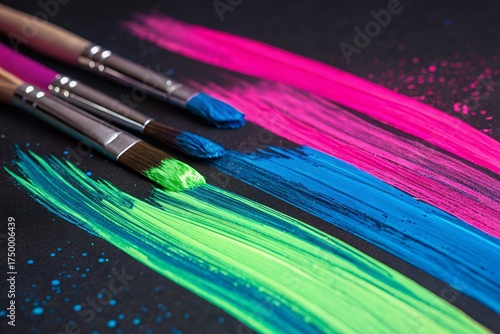 Vibrant neon paint strokes created by artist brushes on dark surface