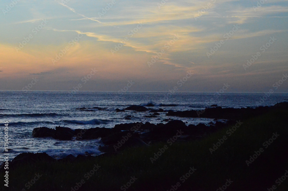 Fototapeta premium Twilight over the Atlantic Ocean near Santa María de Oia, Galicia, Spain, with soft waves, rocky shore, and colorful skies blending into the serene horizon 