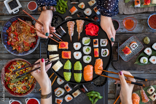 Japanese sushi rolls like Philadelphia roll, dragon roll and California roll with salmon, crab and calamari, Unrecognizable people enjoying a sushi meal with chopsticks