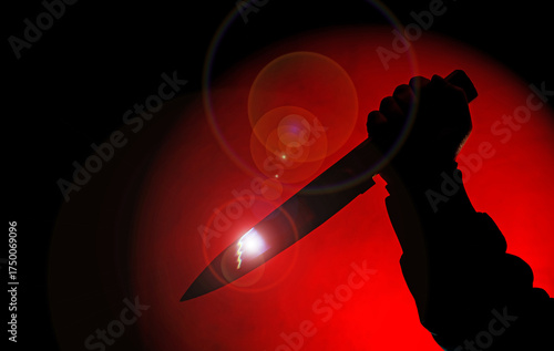 silhouette of scary hand with knife in red spotlight in the darkness.