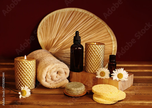 Still life of spa accessories with rolled towels, natural soaps, oils and candles on wooden surface. Warm lighting highlighting textures and neutral tones for wellness and aromatherapy visuals