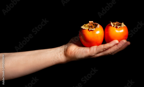 persimmon in hand isolated on black
