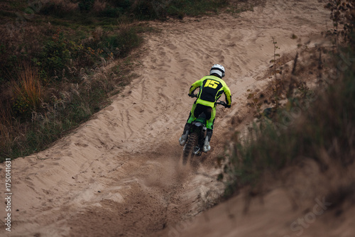 Motorcyclists on a cross-country motorcycle go fast at the desert with sands splashes