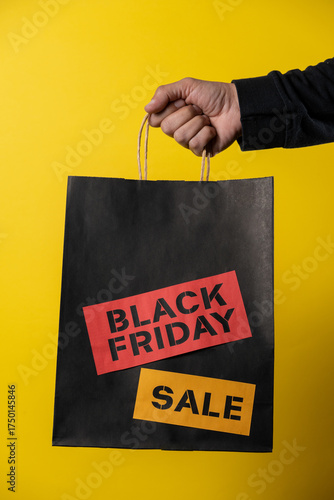Customer holding black friday shopping bag on yellow background