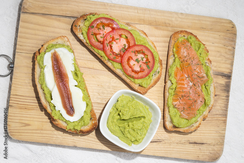 Different tapas: slices of bread with avocado, mozzarella cheese and anchovy, salmon and thyme, tomato and parsley,