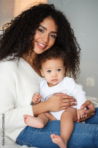 Loving mother holding her baby at home. Tender family portrait showing warmth, care, and emotional bond between parent and child in natural light and cozy atmosphere.