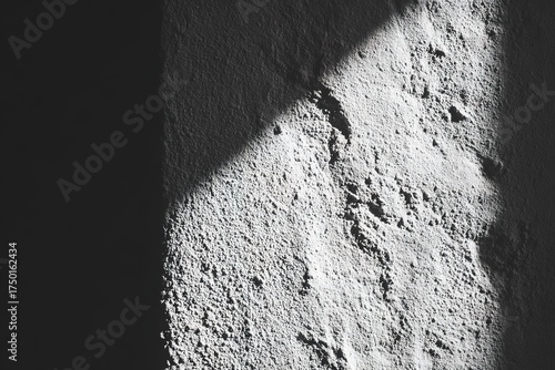 Light creates a dramatic contrast on a textured white wall in an indoor setting during the afternoon