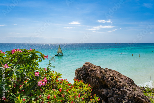 Bild auf Leinwand Breathtaking view of Nungwi Beach in Zanzibar, Tanzania, featuring a traditional dhow sailing on crystal-clear turquoise waters under a vibrant tropical sky