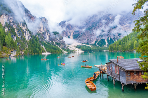 Fototapeta Naklejka Na Ścianę i Meble -  Emerald waters mirror towering Dolomites at Lake Braies, Italy. A serene alpine lake surrounded by pine forests, wooden boats, and dramatic mountain peaks in perfect natural harmony.