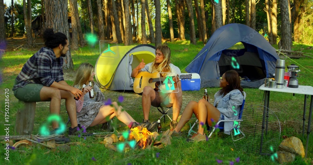Fototapeta premium Sitting around campfire four friends chatting in forest clearing, with acoustic guitar, tents